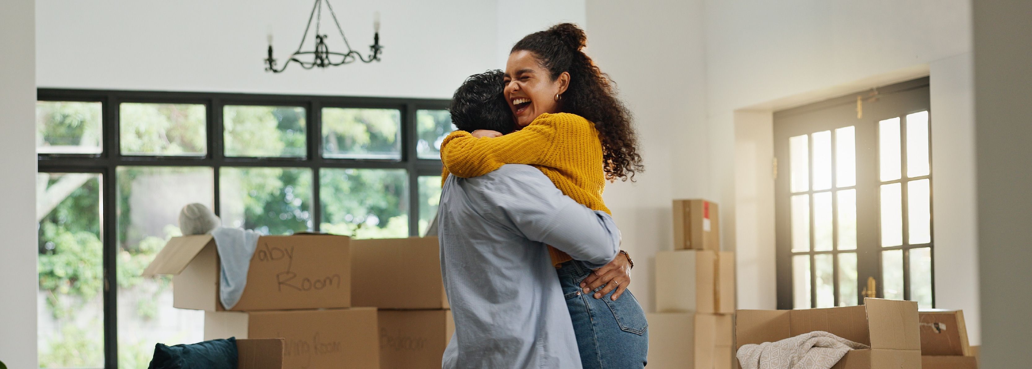 Happy couple embraces in their newly purchased home with boxes to unpack spread around them