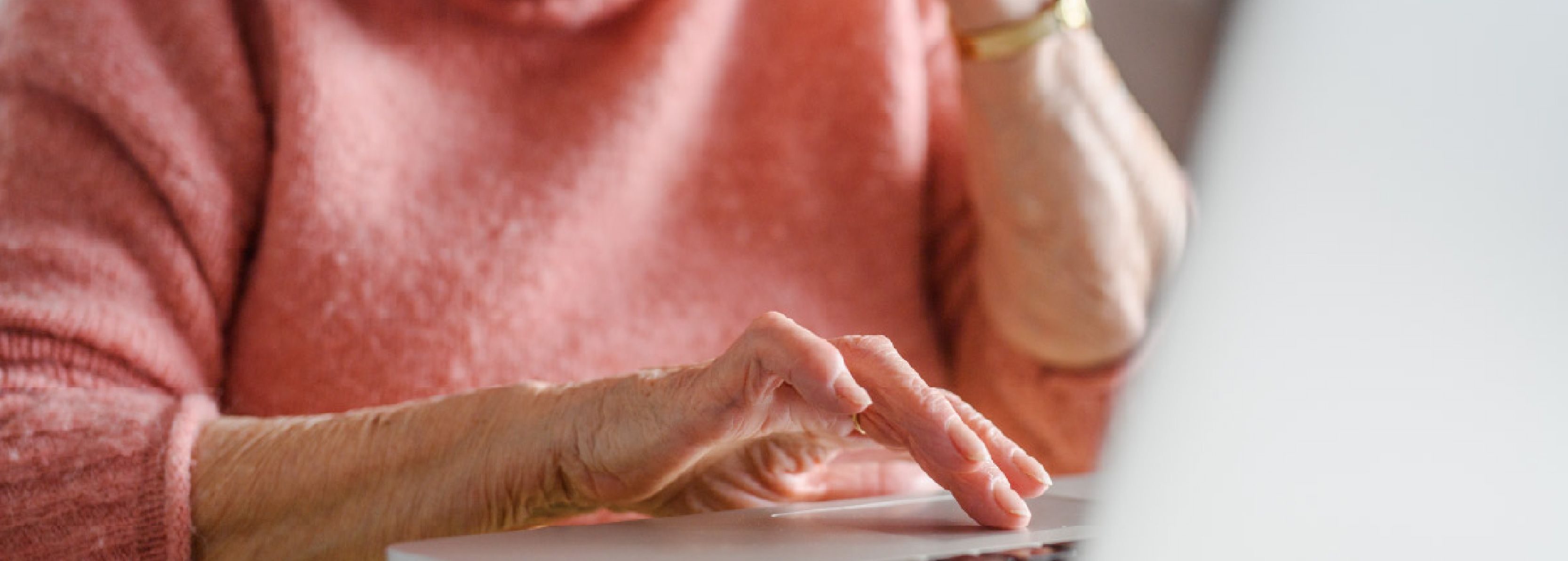 Elderly woman talking on the phone and scrolling on her laptop