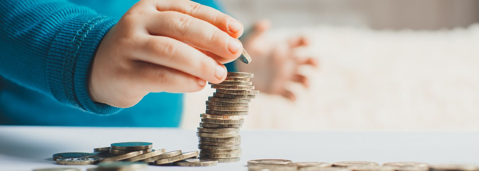 A kid adds a nickel to a stack of coins.