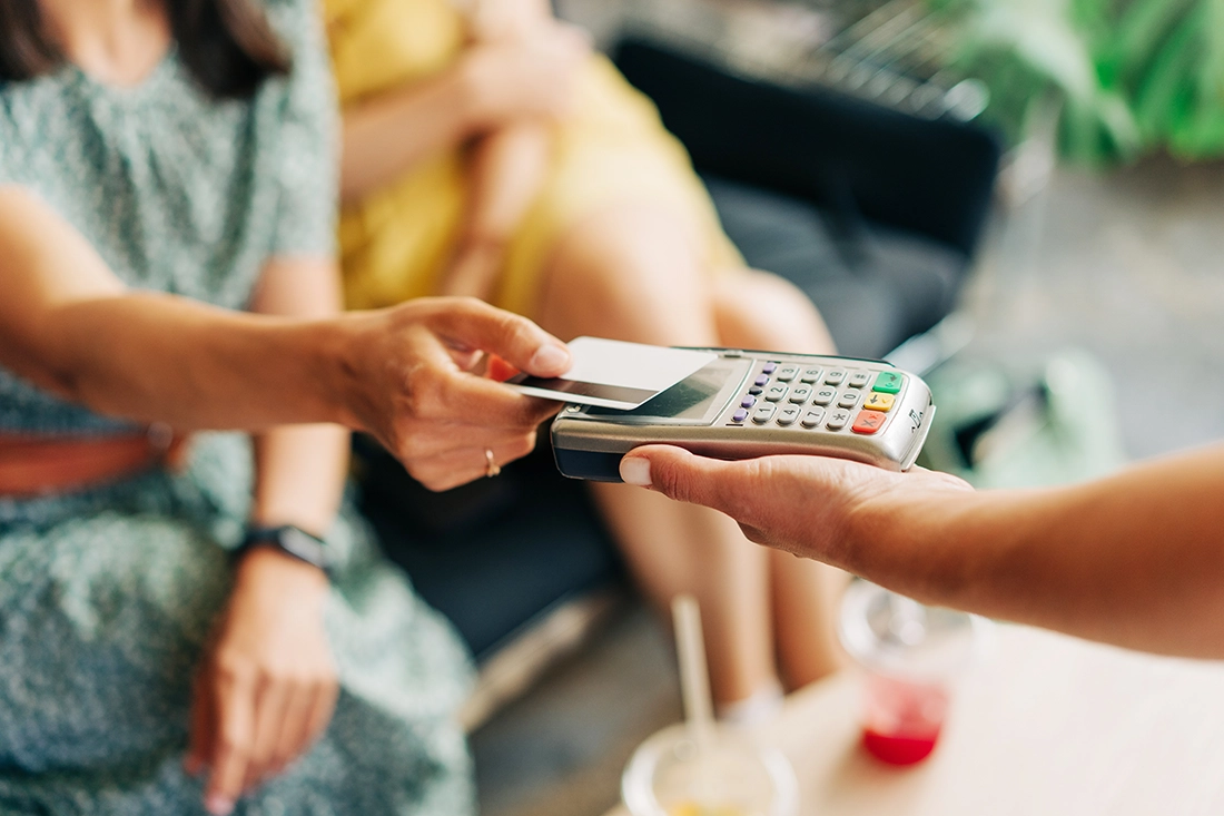 two females having drinks and paying with a debit card.