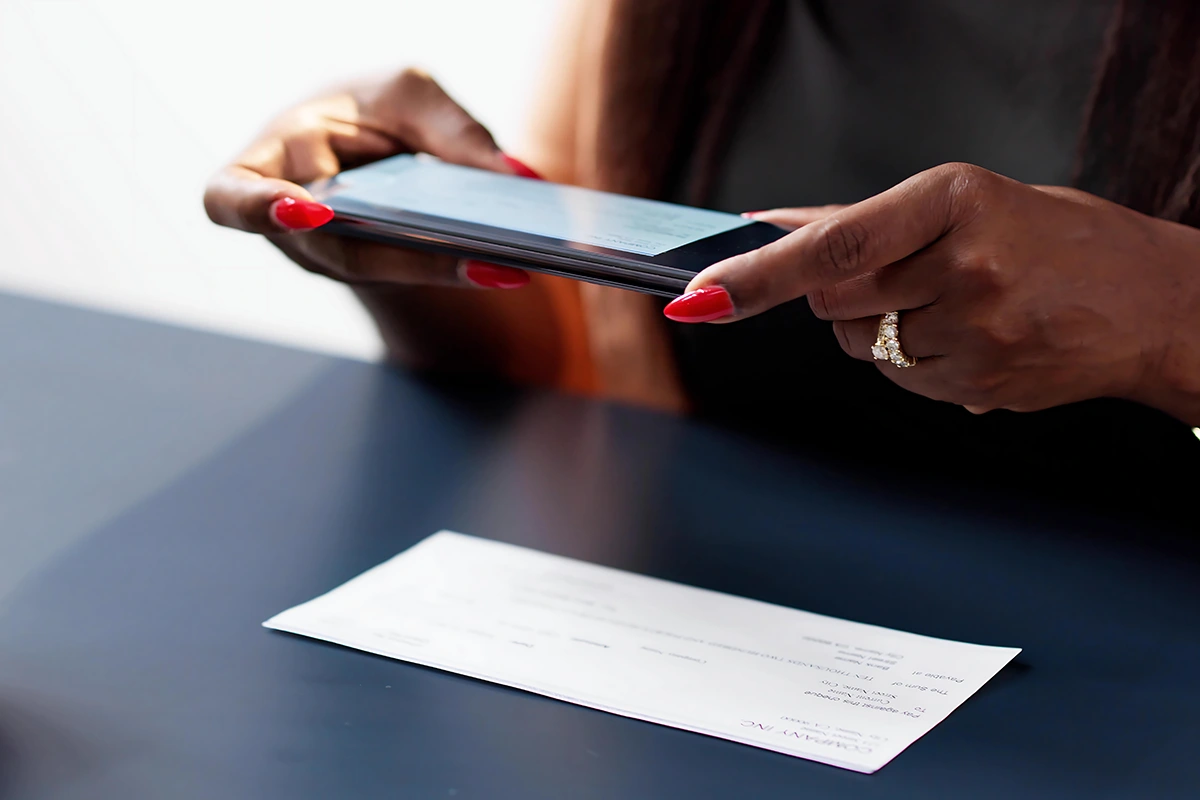 woman using mobile phone to deposit check