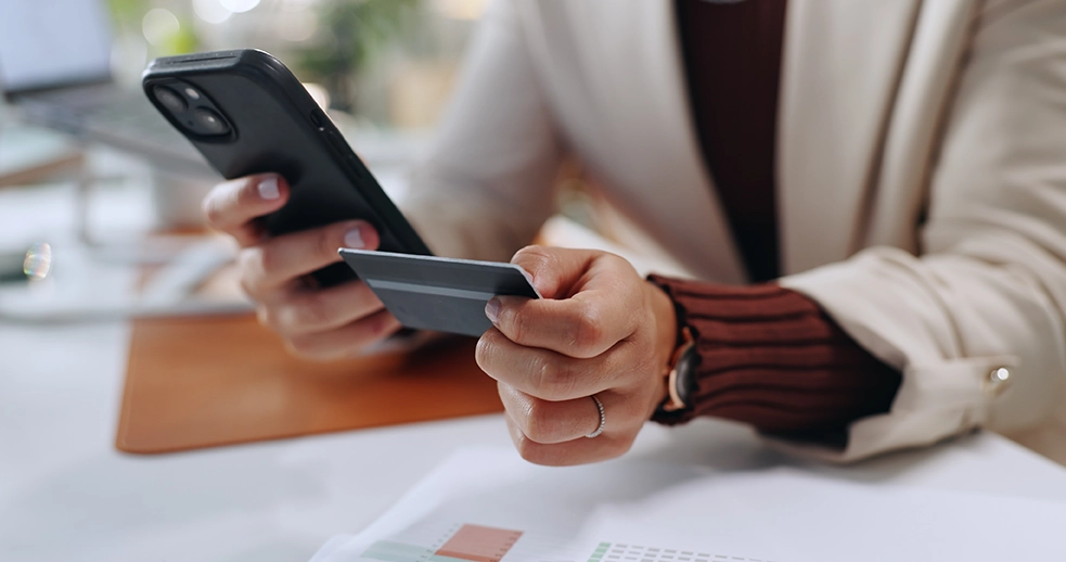 Person holding smartphone and credit card.