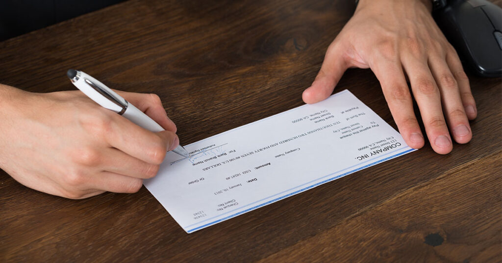 Business person signs a company check