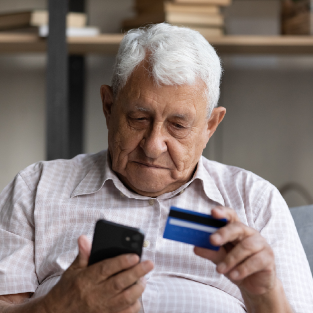 Older man holding cell phone and debit card