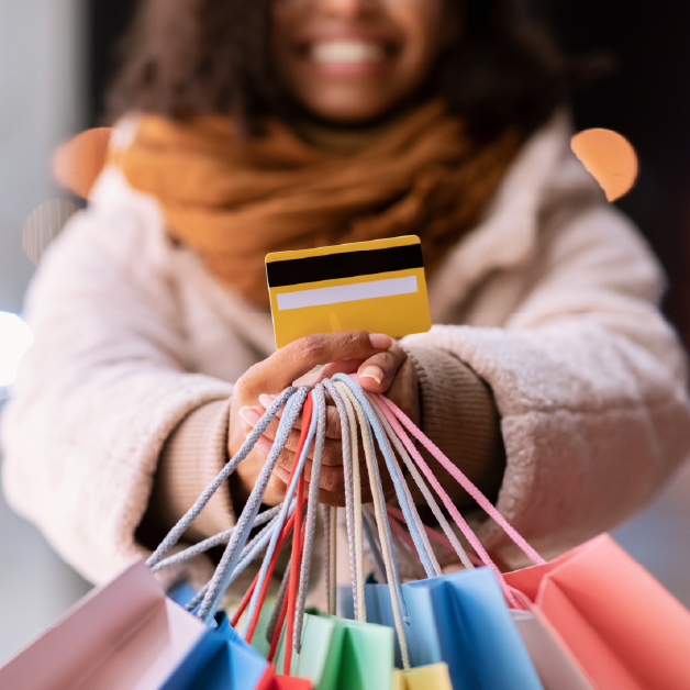 Smiling woman holding her debit card along with her shopping bags