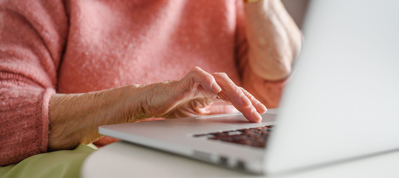 Elderly woman on the phone while looking at her laptop