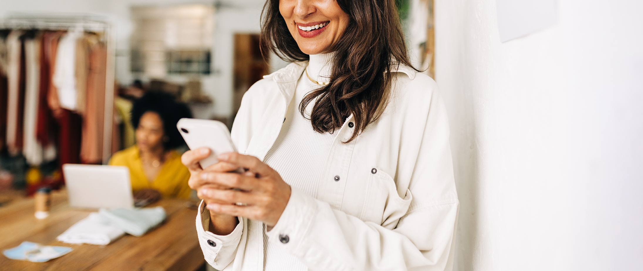 Small business owner smiling while looking at her phone.