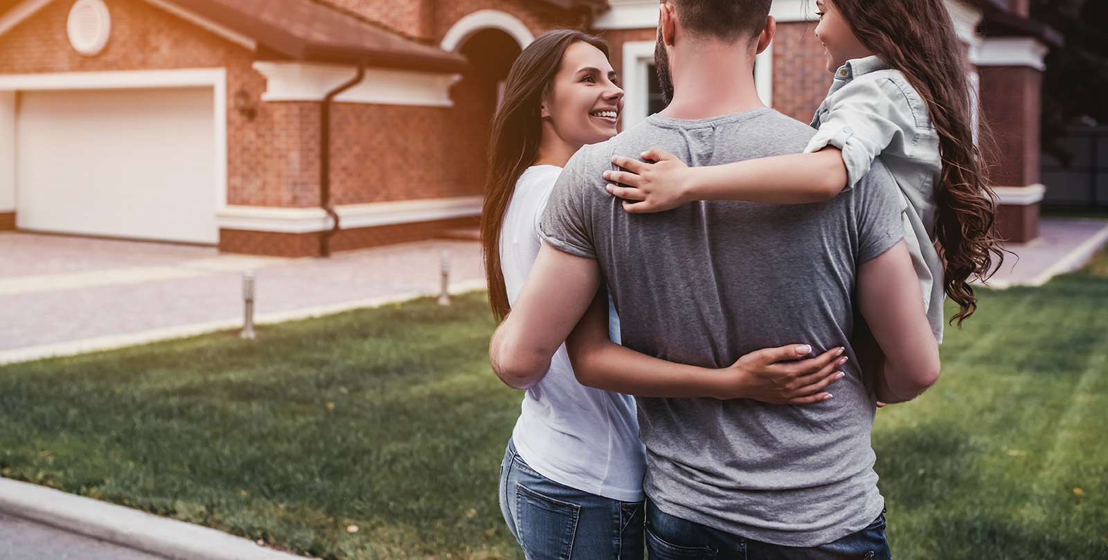 Back view of happy family is standing near their modern house and hugging
