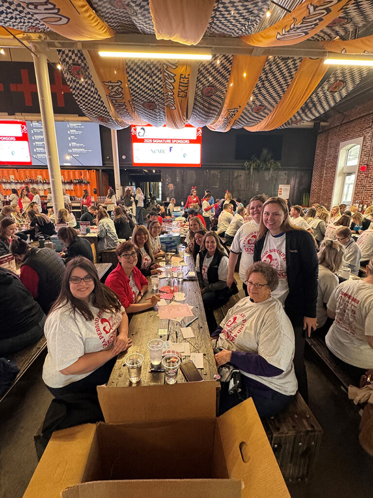 West Bankers sitting at a table smiling during Give Grace, Give Hope's annual Period Packing Party.