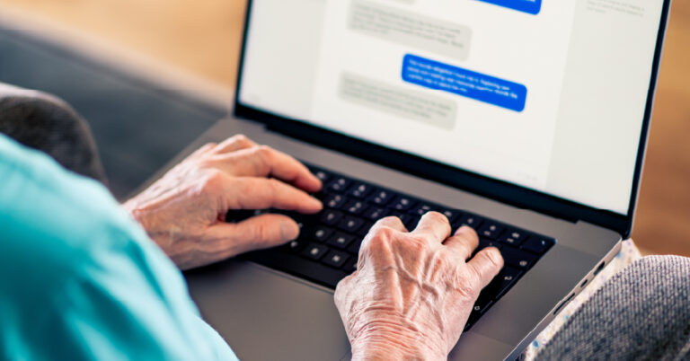 Elderly woman messages someone online on her laptop