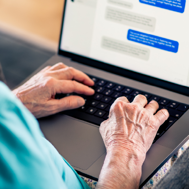 Elderly woman messages someone online on her laptop
