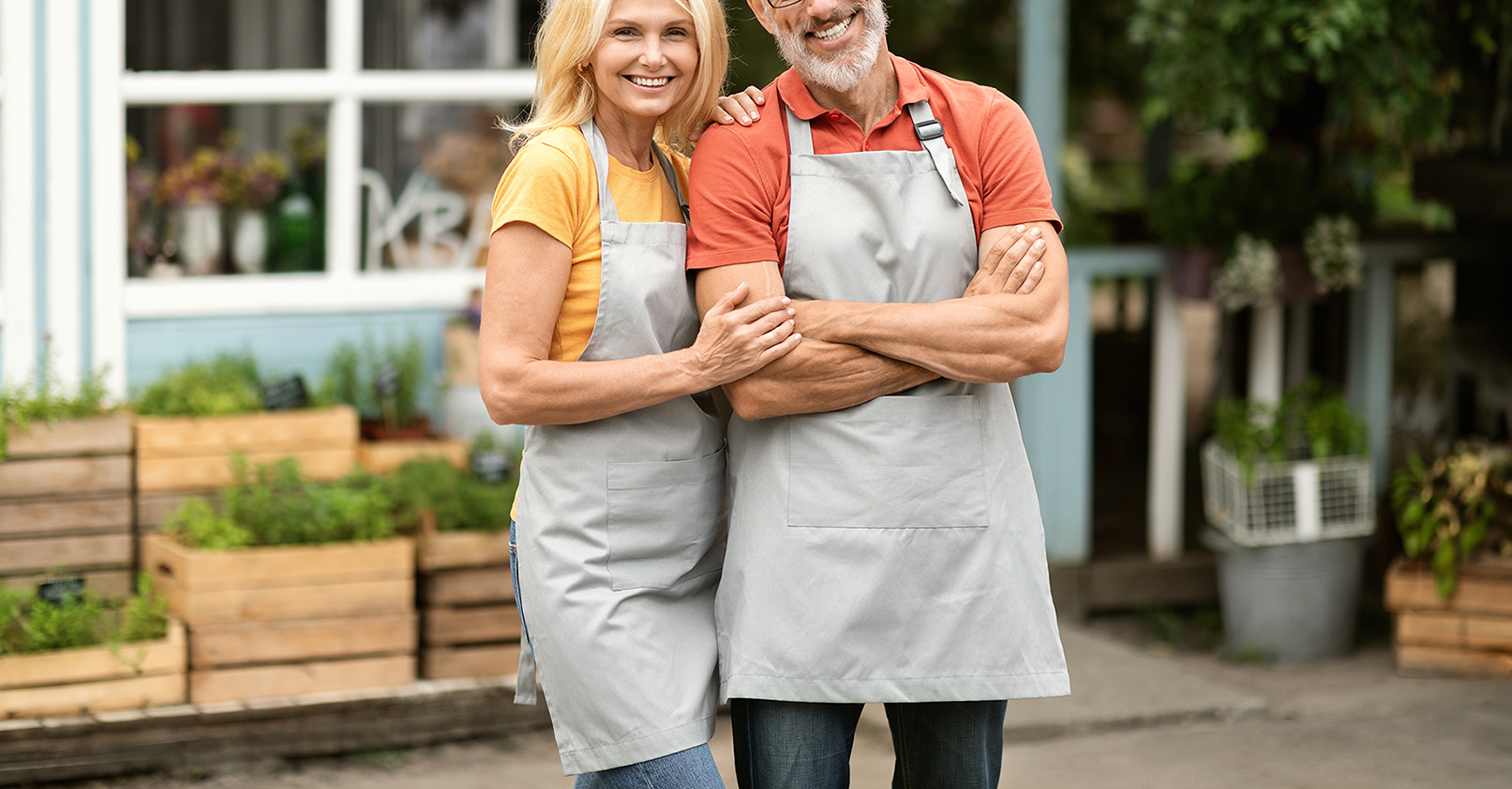 Portrait Of Happy small business owner Couple Standing Outdoors Near Their Greenhouse.