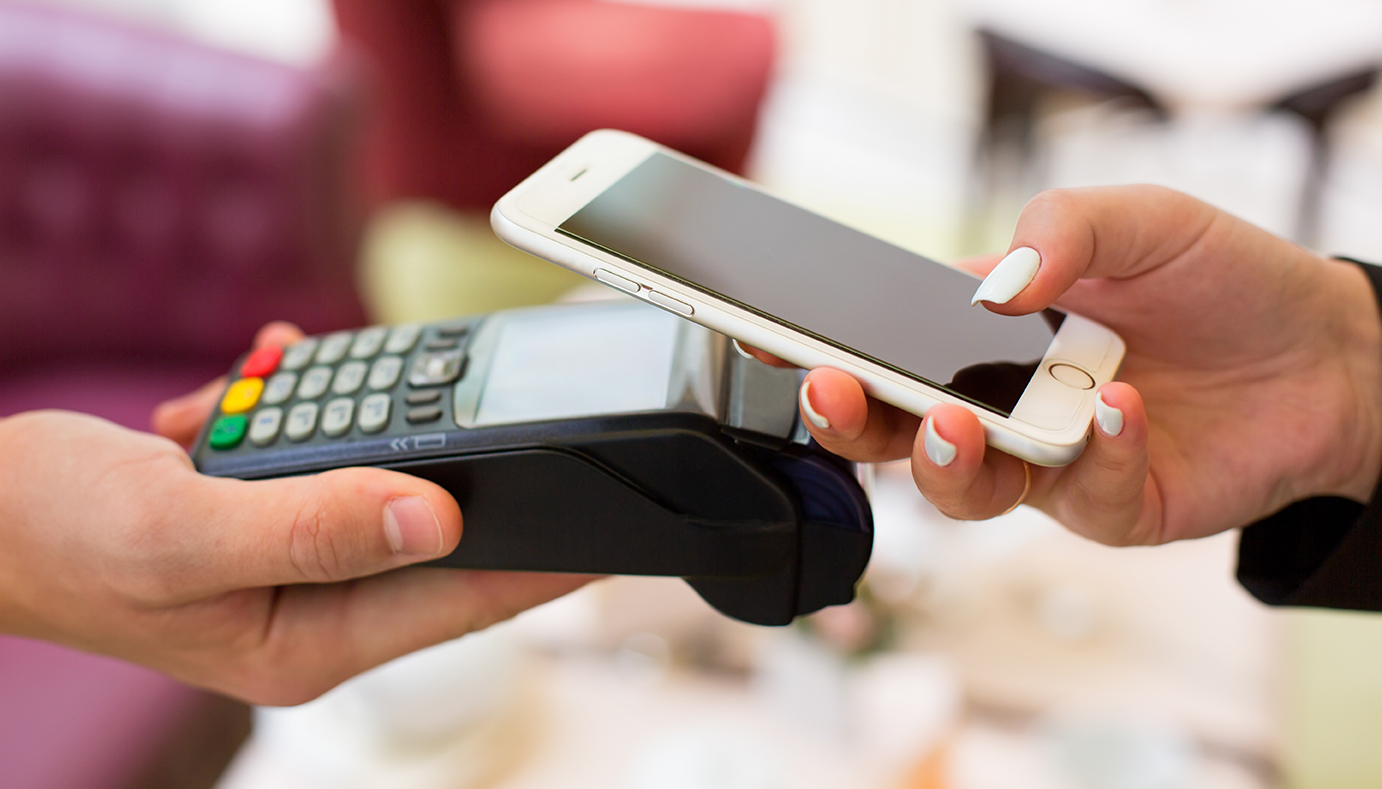 Female paying with NFC technology on smart phone, hands close up. Woman using mobile phone for pay by the bill.