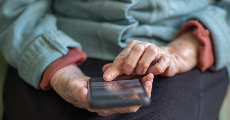 Elderly woman taps on her smartphone screen