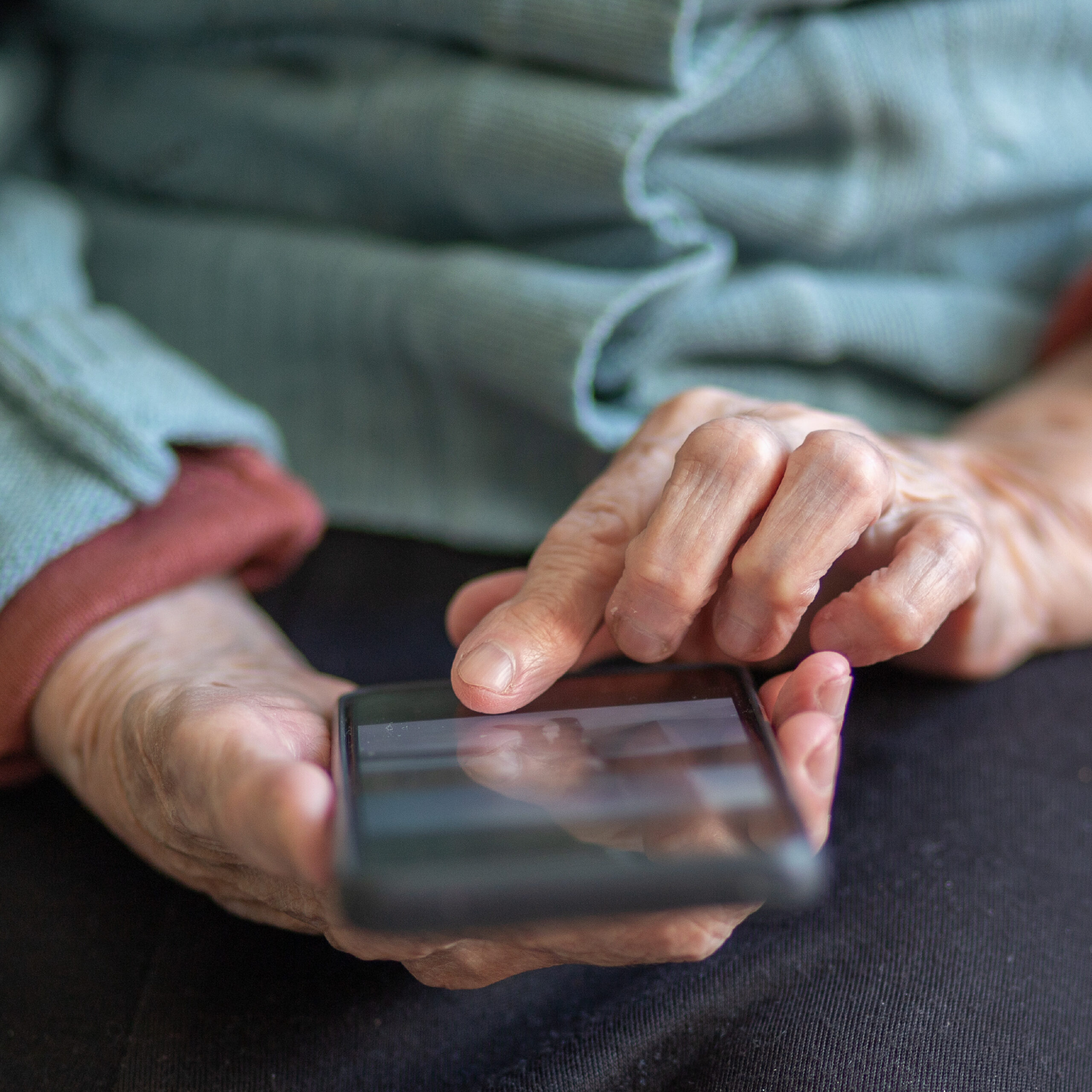 Elderly woman taps on her smartphone screen