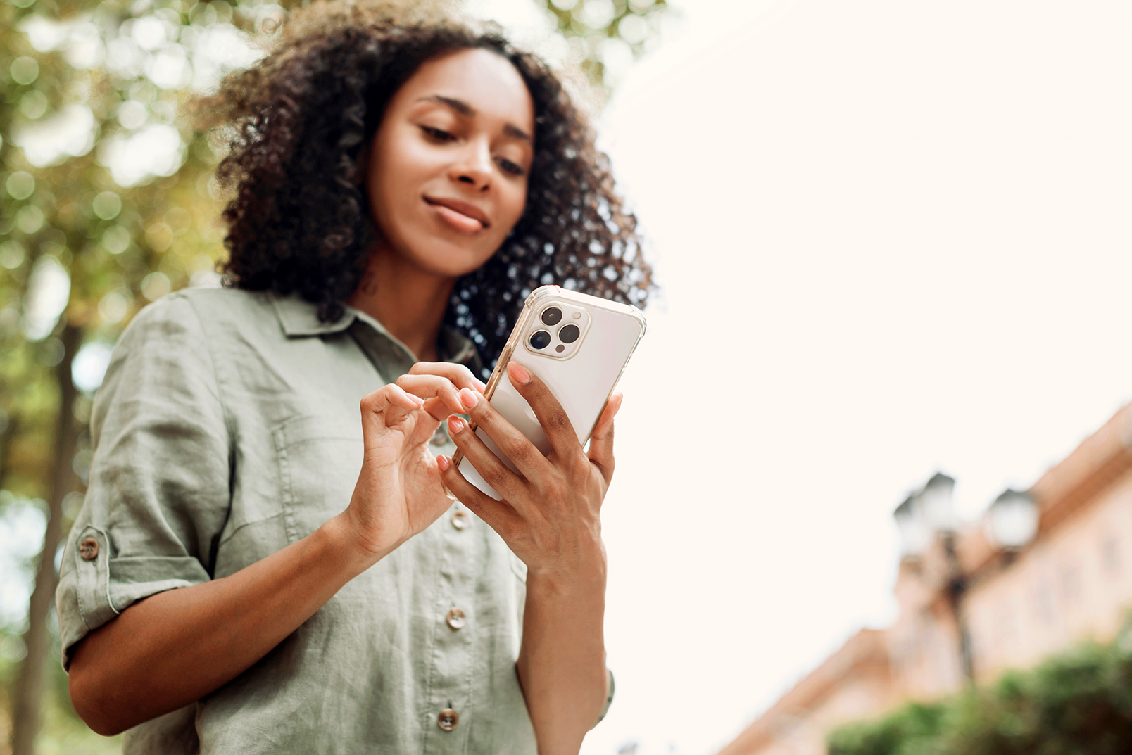 Smiling woman looking at mobile phone outdoors, focus on phone