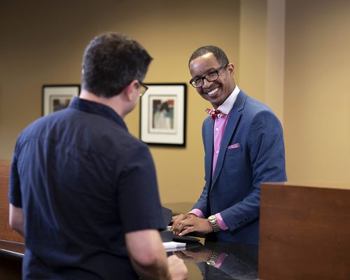 Teller Richard Mockobee looks up a customers account information while smiling