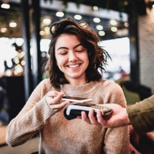 Young female with wavy hair using mobile wallet in a restaurant