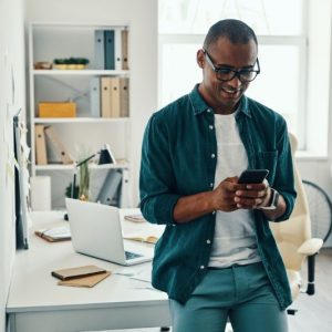 Male in home office smiling at his smartphone.